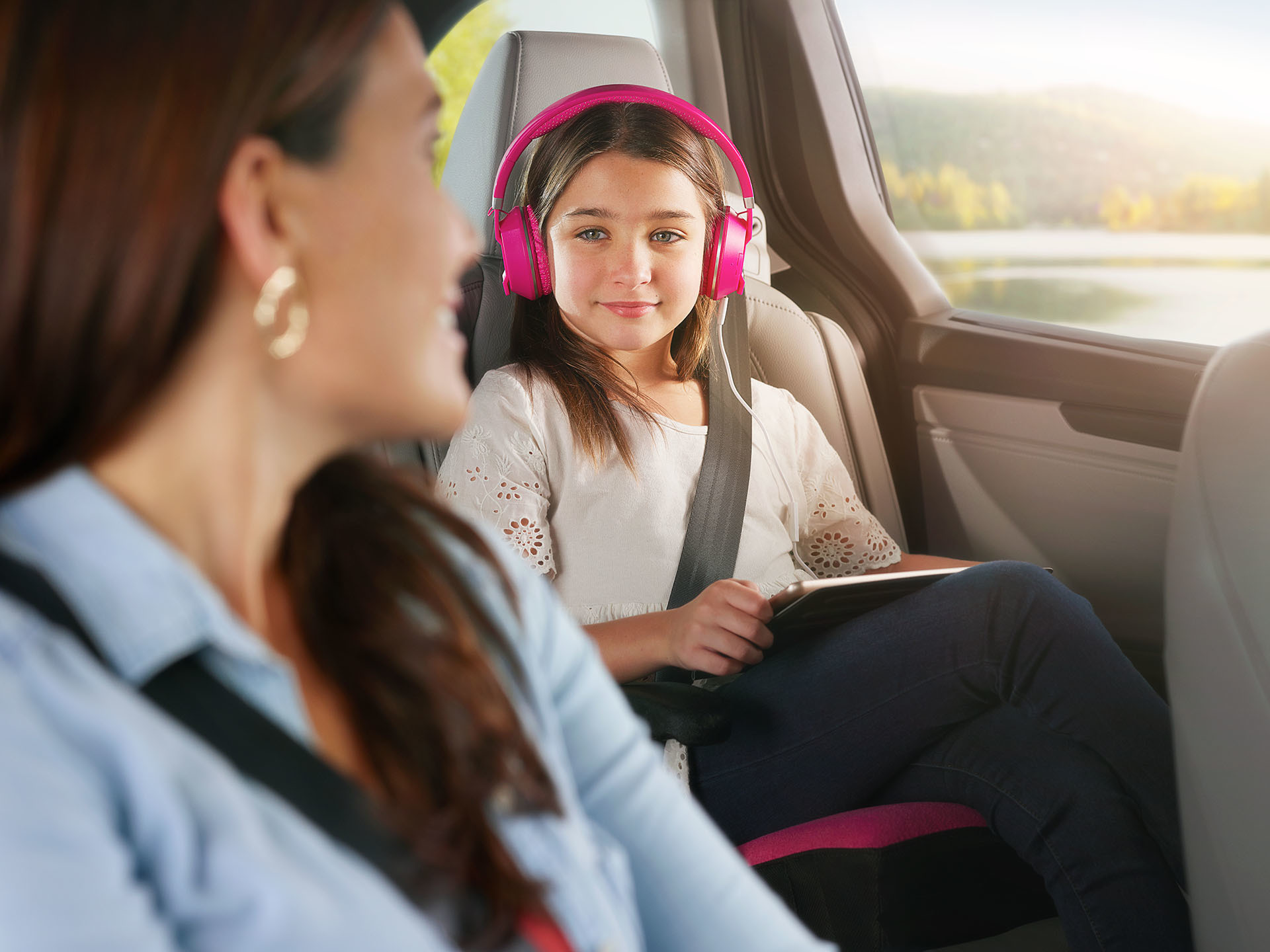 Daughter in headphones looking at mom during roadtrip